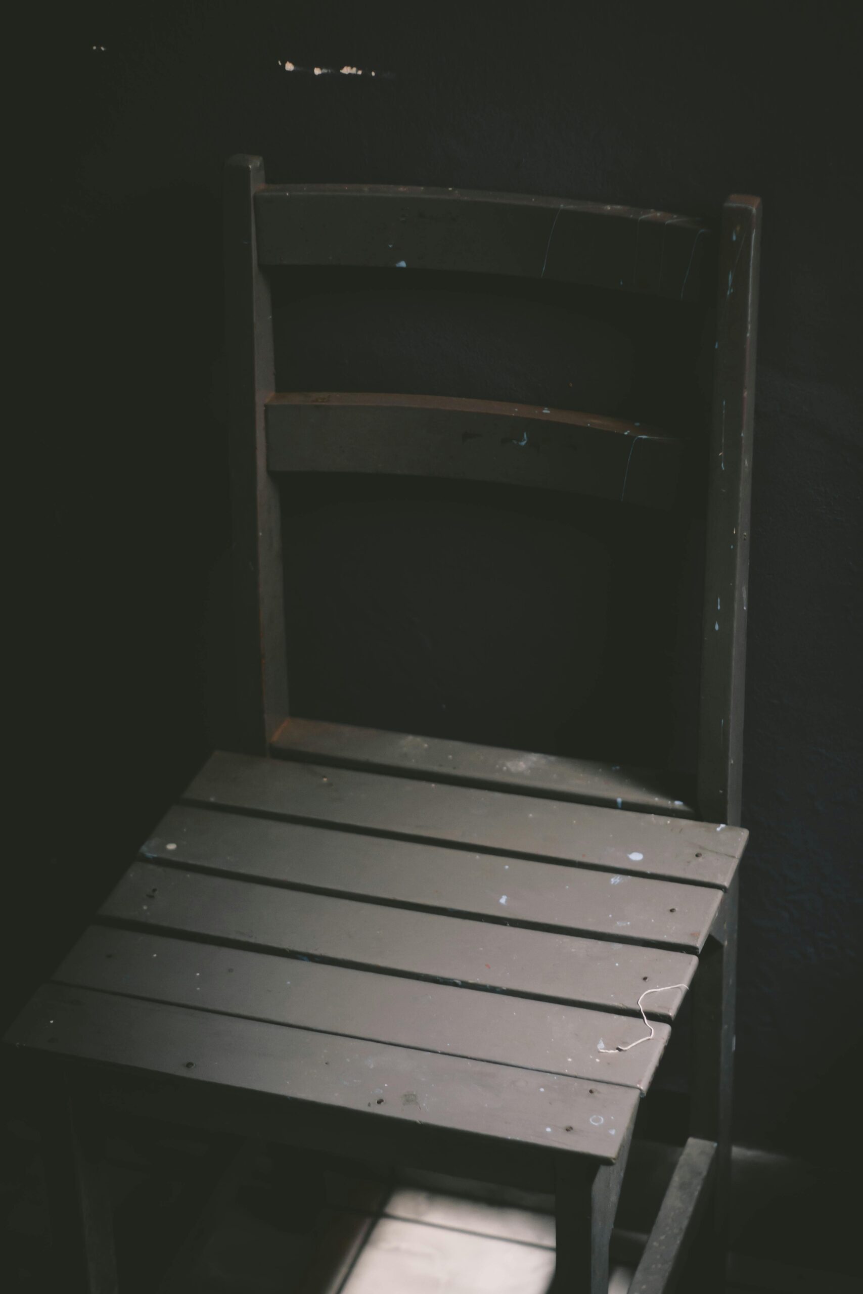 Black and white of wooden minimalist chair placed in dark room in ray of sunlight