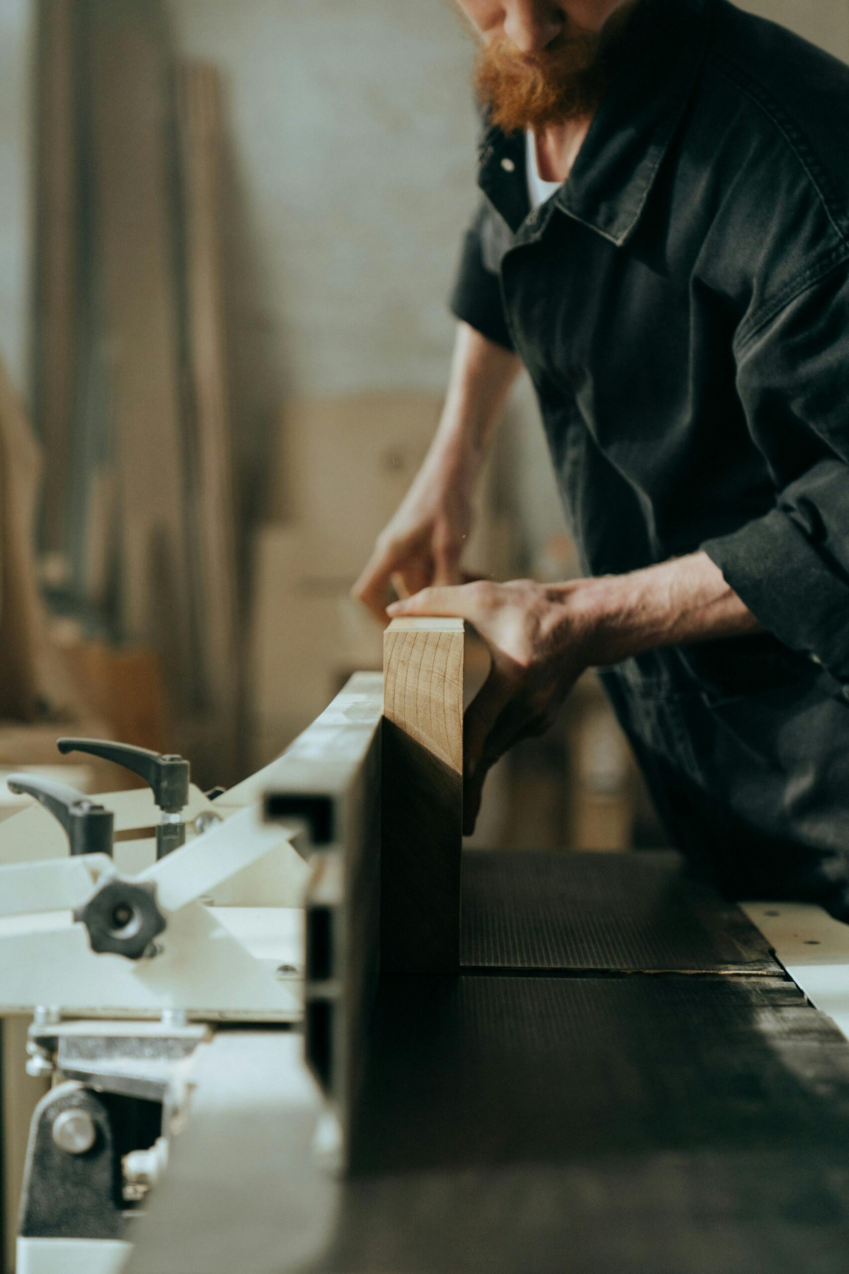 A focused craftsman working on woodworking with a saw in a workshop setting.