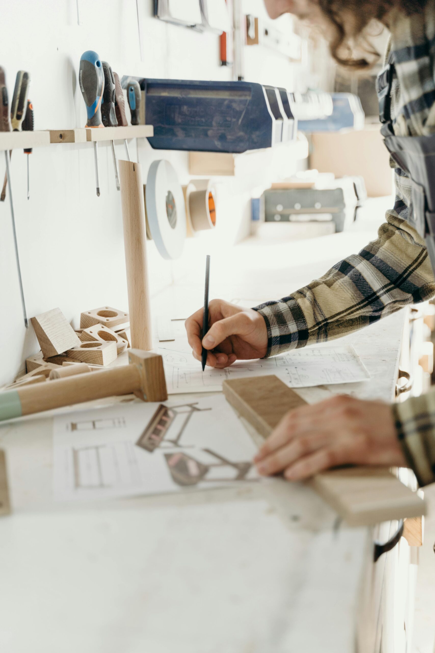 A craftsman working diligently in a woodworking workshop, sketching designs.